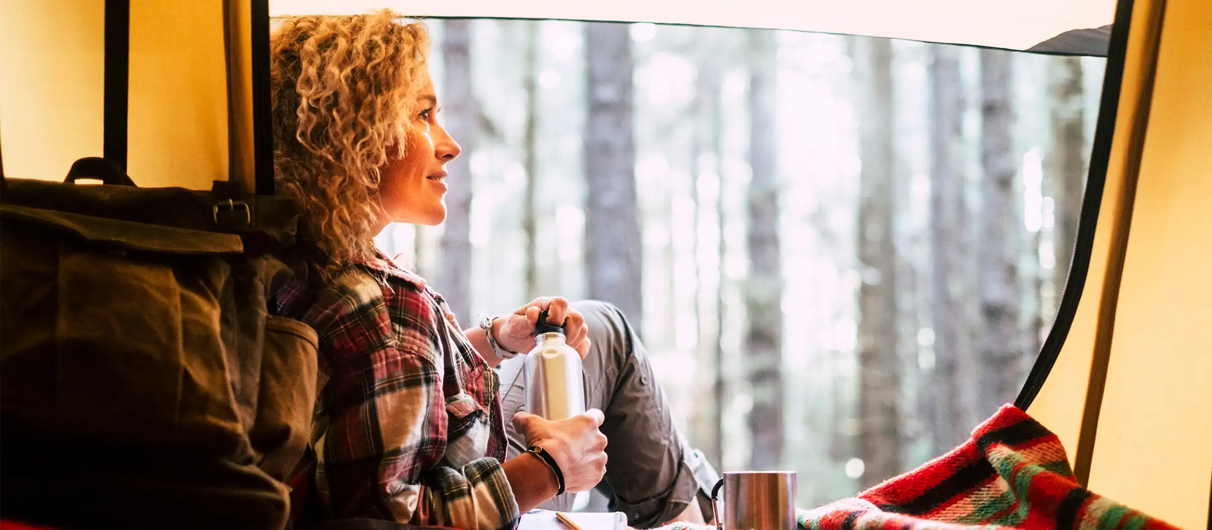 middle aged woman admiring nature from inside her tent