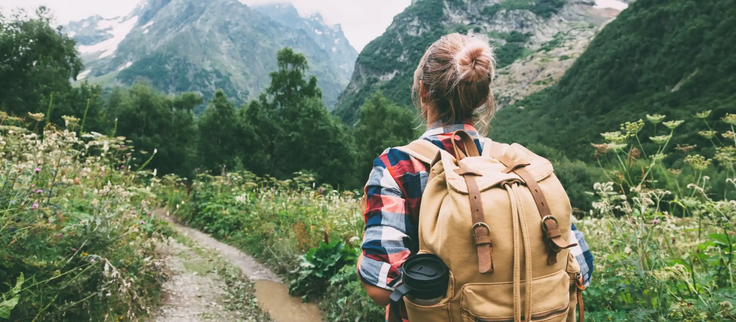 young woman hiking with backpack through mountain valley