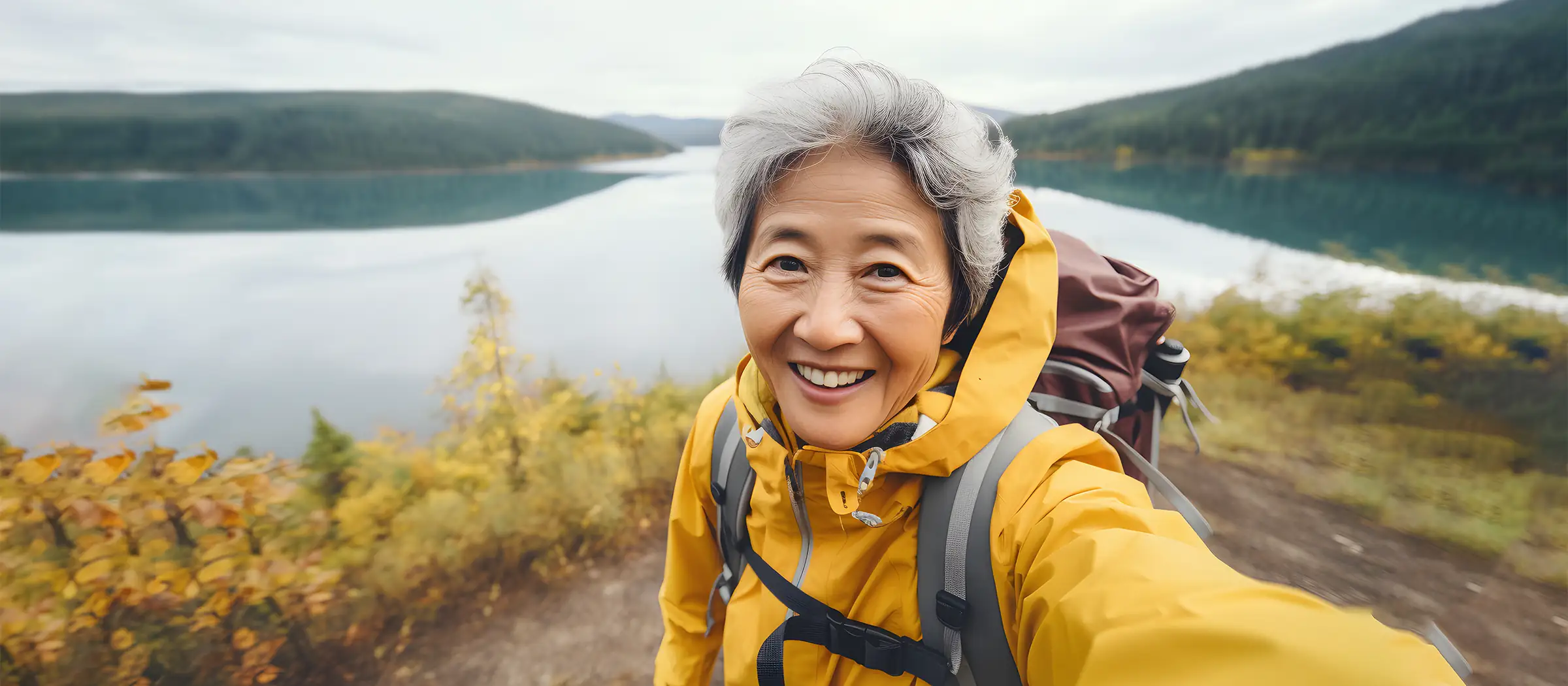 senior asian woman taking picture by the lake while hiking