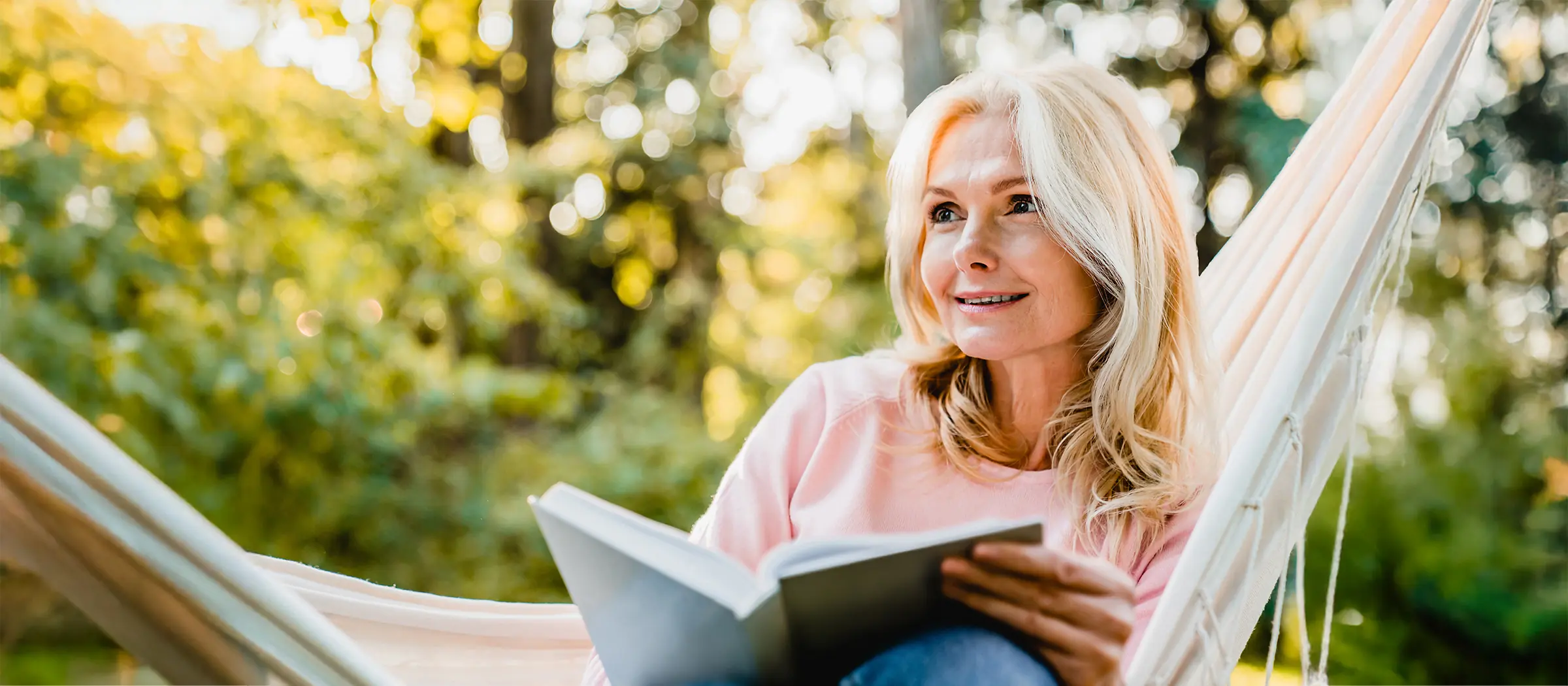 mature woman enjoying book in hammock